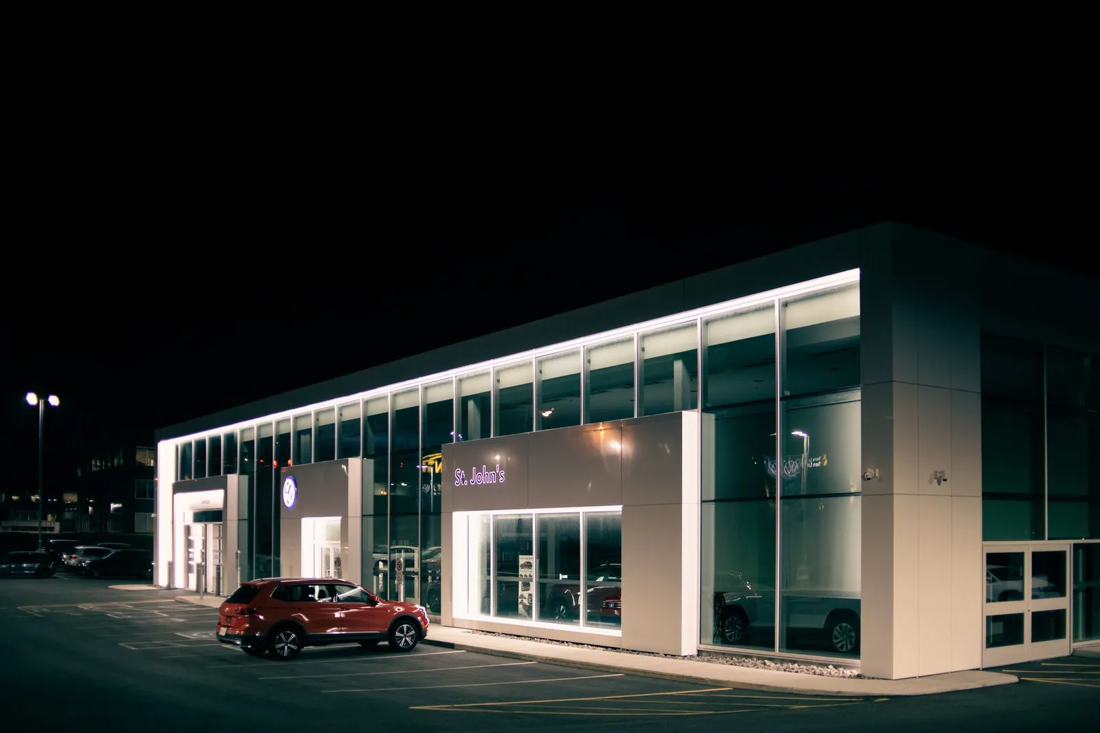 Façade vitrée d'une concession automobile éclairée la nuit
